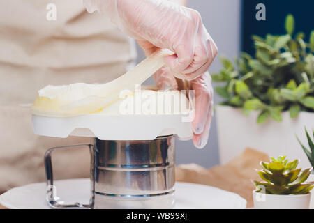 Pasticcere fa una torta di nozze con borsa di pasticceria in cucina Foto Stock