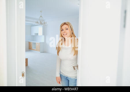 Allegro giovane donna che invita la gente a entrare in casa. Foto Stock