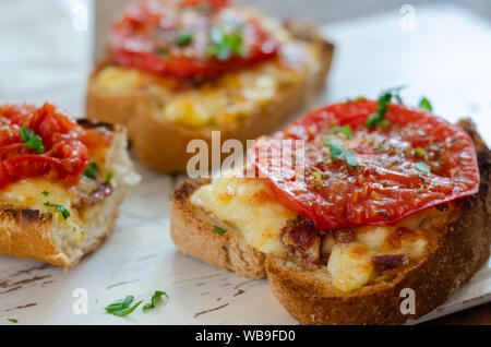 Il pane integrale è fatta di grigliate con vari formaggi su tagliate a fette e servite con le fette di pomodoro e timo-prezzemolo sulla parte superiore. Foto Stock