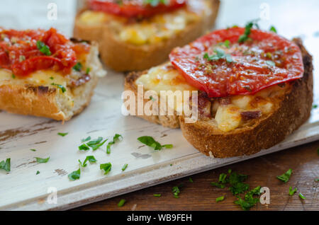 Il pane integrale è fatta di grigliate con vari formaggi su tagliate a fette e servite con le fette di pomodoro e timo-prezzemolo sulla parte superiore. Foto Stock