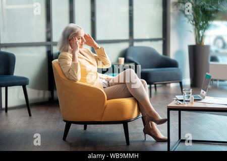 Senior imprenditrice che soffrono di mal di testa in ufficio Foto Stock