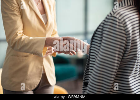 Due femmina caucasica stringono le mani in ufficio Foto Stock