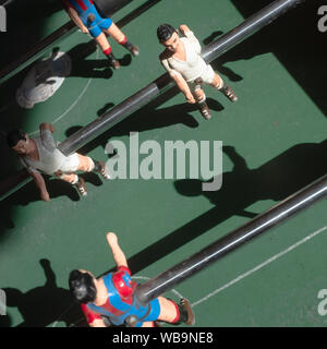 Figurine di giocatori di calcio su una vecchia tabella di foosball. Direttamente al di sopra di vista. Le rivalità e i concetti di lavoro di squadra. Foto Stock