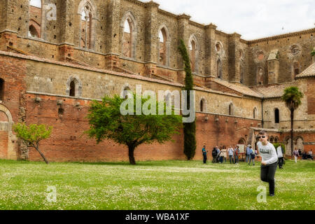 Chiusdino/Toscana, Italia - 25 Aprile 2019: picnic e giovane ragazzo che corre lungo i motivi dell'abbandonata Abbazia di San Galgano Foto Stock