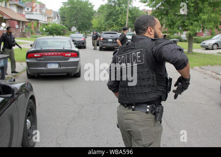 Detroit il dipartimento di polizia per le operazioni speciali cassetti officer la sua pistola come egli si prepara per avvicinarsi a una casa come il loro aspetto per un sospetto, Detroit, Michigan, Stati Uniti d'America Foto Stock