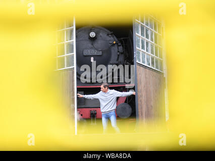 20 agosto 2019, Assia, Darmstadt: Uwe Breitmeier, primo presidente del mondo ferroviario Darmstadt-Kranichstein, apre un gate della locomotiva sparso sul terreno del museo, dietro la quale si erge una classe 41 locomotiva a vapore. Sulla vasta area dell'ex Darmstadt cantiere di smistamento si possono sperimentare la storia ferroviaria. Fondata nel 1970 con la ferrovia appassionati, l'associazione ha raccolto e procurato 45 locomotive, intorno a 150 carri e macchine per le riparazioni e la manutenzione. (A dpa "Ferrovia romanticismo ha il suo prezzo - circa 50 museo delle ferrovie in Germania") Foto: Arne Dedert/dpa Foto Stock