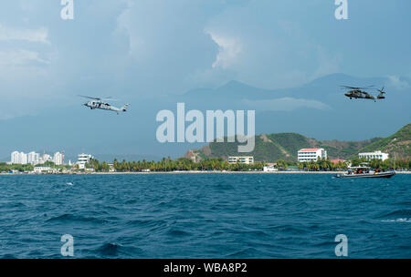 Un U.S. Navy MH-60S Seahawk assegnato al 'Dragon balene' di elicottero di mare squadrone di combattimento (HSC) 28, sinistra, attaccato alla nave ospedale USNS Comfort (T-AH 20), vola con un esercito colombiano elicottero al largo della costa di Santa Marta, Colombia, durante un volo di formazione con l'esercito colombiano, Agosto 23, 2019. Il comfort è il lavoro con la salute e i collaboratori del governo in America Centrale, Sud America e Caraibi per fornire assistenza sulla nave e a terra a base di siti medici, contribuendo ad alleviare la pressione sul National Medical Systems teso da un aumento di migranti venezuelano. (U.S. Navy foto di Foto Stock