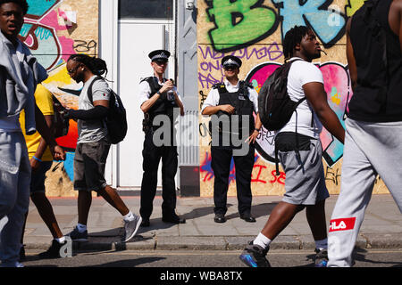 Londra, Regno Unito. 25 Ago, 2019. Gli ufficiali di polizia sostare di fronte imbarcati-negozi su Westbourne Grove, durante il giorno di apertura del 2019 carnevale di Notting Hill.fino a un milione di persone sono attese a pacco le strade di Notting Hill e le aree circostanti nel corso dei due giorni della manifestazione. La celebrazione annuale della cultura afro-caraibica si svolge ogni ferragosto weekend. Credito: SOPA Immagini limitata/Alamy Live News Foto Stock