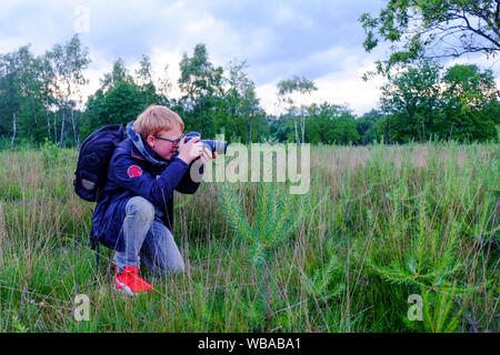 Giovane fotografo nel campo Apri tenendo la natura fotografie all'aperto con una fotocamera reflex digitale Foto Stock