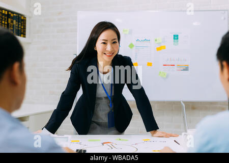 Asian business maturo donna sorridente e discutendo con altri uomini di affari. Un gruppo di persone di affari in riunione. Foto Stock