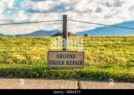 In prossimità di una messa a terra sotto il segno di riparazione su un terreno erboso lungo una strada pavimentata Foto Stock