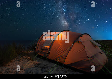 Una tenda da campeggio e una Via Lattea su una spiaggia vicino al mare Foto Stock