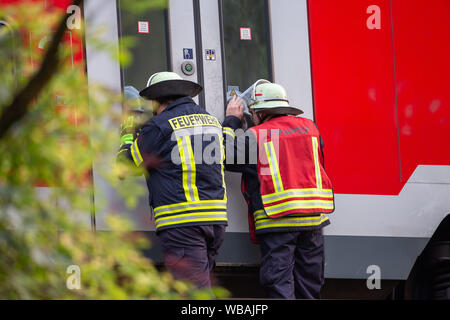 24 agosto 2019, Sassonia, Bad Schandau: due vigili del fuoco timido nel treno per assicurarsi che non vi è alcuna persona in più. Nello scenario dell'esercitazione si ipotizza che una grave situazione di tempesta con forti precipitazioni e tempeste prevarrà nella zona della capitale dello stato di Dresda come pure nei distretti di Bautzen e sassoni Switzerland-Osterzgebirge per diversi giorni. Intorno a 5 p.m., un treno EC con 300 passeggeri sarà in viaggio verso Praga nella valle dell'Elba, vicino al confine con la Repubblica ceca, dove sarà colpito da una frana causata dalla pioggia persistente che h Foto Stock