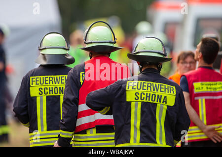 24 agosto 2019, Sassonia, Bad Schandau: Vigili del Fuoco del volontario vigili del fuoco Schöna vai al sito incidente a piedi. Nello scenario dell'esercitazione si ipotizza che una grave situazione di tempesta con forti precipitazioni e tempeste prevarrà nella zona della capitale dello stato di Dresda come pure nei distretti di Bautzen e sassoni Switzerland-Osterzgebirge per diversi giorni. Intorno a 5 p.m., un treno EC con 300 passeggeri sarà in viaggio verso Praga nella valle dell'Elba, vicino al confine con la Repubblica ceca, dove sarà colpito da una frana causata dalla pioggia persistente che ha bu Foto Stock