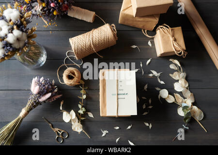 Al di sopra di vista dei doni confezionati su tavola con petali disordinati Foto Stock