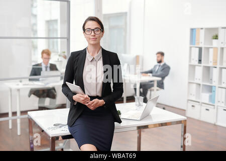 Ritratto di elegante imprenditrice con gli occhiali in posa di office Foto Stock