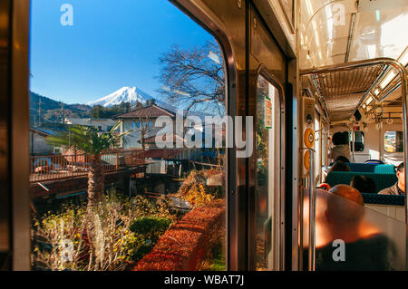 30 NOV 2018 Fujiyoshida, Giappone - coperta di neve sul monte Fuji dietro città locali lungo il percorso del treno da Tokyo a Kawaguchiko visto attraverso la finestra del treno con Foto Stock