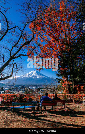 30 NOV 2018 Fujiyoshida, Giappone - Monte Fuji e rosso acero con dolci turista giovane sedersi sulla panchina alla Pagoda Chureito Arakurayama Sengen Park Fuj Foto Stock