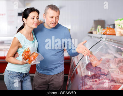 Coppia positiva ai clienti la scelta di carne in macelleria Foto Stock