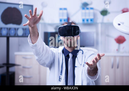 Ritratto di giovane medico con la tecnologia della realtà virtuale per problemi di salute. Medico che indossa la realtà virtuale auricolare. Foto Stock