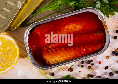 Aprire può di filetti di sgombro in salsa di pomodoro sulla tavola di legno Foto Stock