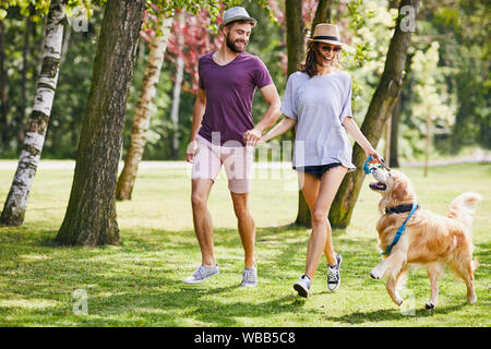 Coppia giovane correre e giocare con il loro cane mentre fuori su una passeggiata Foto Stock