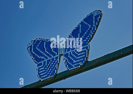 Abstract blue butterfly contro un cielo blu al di fuori dell'entrata alla Butterfly Farm in Stratford upon Avon, Warwickshire Foto Stock