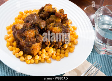 Brasati oxtails con ceci su una piastra bianca Foto Stock