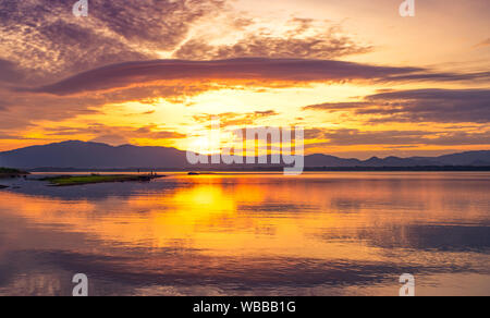 Beautiful golden sky al mattino con sunrise oltre la gamma della montagna e lago o fiume. Paesaggio di serbatoio e montagna. Tranquillo e calmo Foto Stock