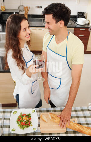 Giovane coppia felice in amore cena di cucina e di bere il vino in casa Foto Stock