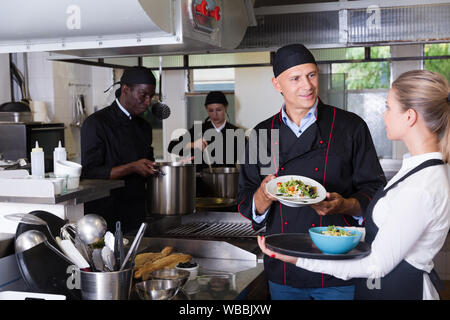 Il personale del ristorante con chef lavorano insieme in cucina Foto Stock