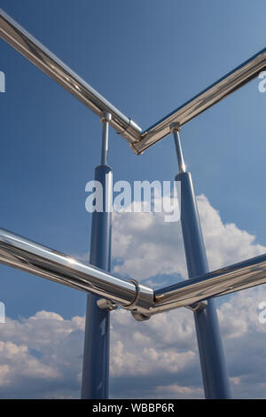 Acciaio inossidabile ringhiera scale dall'esterno dell'edificio su uno sfondo di cielo blu e nuvole bello. Tubi, cerniere, balaustre fatta di sta Foto Stock