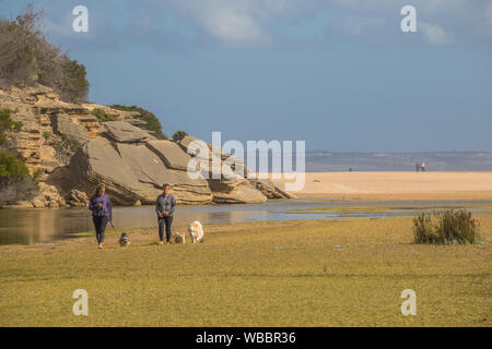 Mossel Bay, Sud Africa - i residenti non identificato a piedi i loro cani presso l'isola alla foce del grande fiume Brak immagine in formato orizzontale Foto Stock