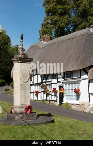 Wherwell, Hampshire, Inghilterra, Regno Unito. Agosto 2019. Vecchie case in paglia e un monumento a coloro che hanno dato la loro vita nella Grande Guerra sul villaggio verde Foto Stock