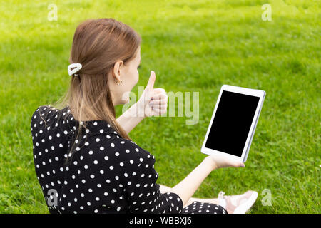 Donna che parla in linea in una video conferenza con un laptop seduto su una panchina in strada Foto Stock