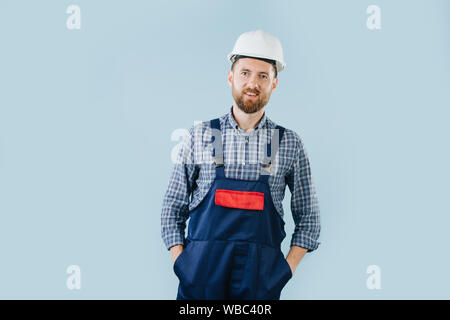 Fiducioso operaio edile in un casco bianco e tute blu Foto Stock