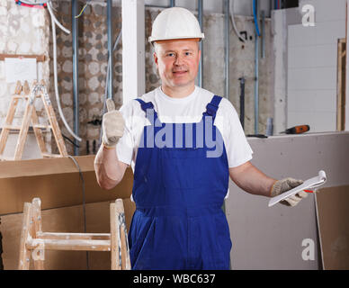 Felice fiducioso costruttore professionale in posa nella camera riparabile Foto Stock