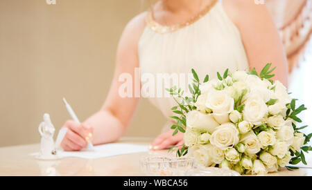 Dettaglio della mano di una sposa che firma l'atto di matrimonio Foto Stock