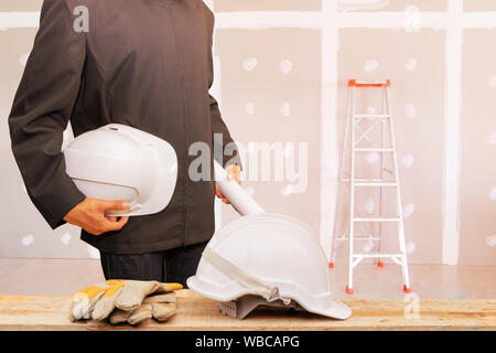 Imprenditore ingegneria tenendo il casco bianco nel lavoro di cartongesso parete decorazione di interni di casa nel sito in costruzione Foto Stock