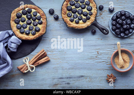 Piatto di laici mirtillo deliziosi pasticcini con crema alla vaniglia crema sulla luce di legno rustico sfondo. Vista da sopra con copy-spazio. Foto Stock