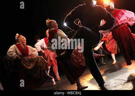 Ballerini folk in estone vestiti nazionali esibirsi sul palco per interni Foto Stock