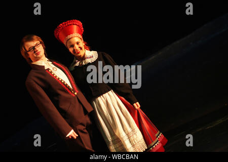 Ballerini folk in estone vestiti nazionali esibirsi sul palco per interni Foto Stock