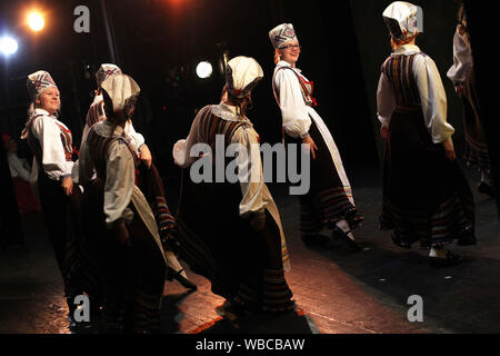 Ballerini folk in estone vestiti nazionali esibirsi sul palco per interni Foto Stock