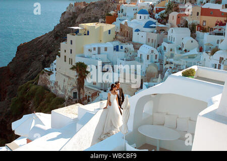 Oia - Santorini, Grecia - 7-07-2016: la sposa e lo sposo che pongono tra Santorini case bianche e blu con vista sul mare. Nozze il concetto di turismo Foto Stock