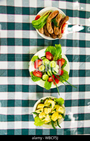 I piatti su tavola - verdure, patate, salsicce bavaresi. Sfondo. Foto Stock