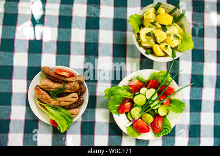 I piatti su tavola - verdure, patate, salsicce bavaresi. Sfondo. Foto Stock