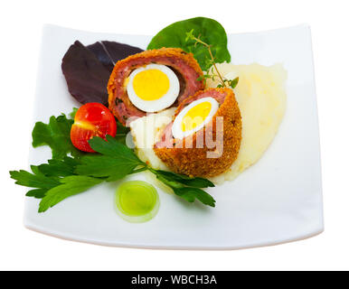 Scotch uova - uova di quaglia avvolti in carne di salsiccia con guarnite di purea di patate, ortaggi e verdure. Isolato su sfondo bianco Foto Stock