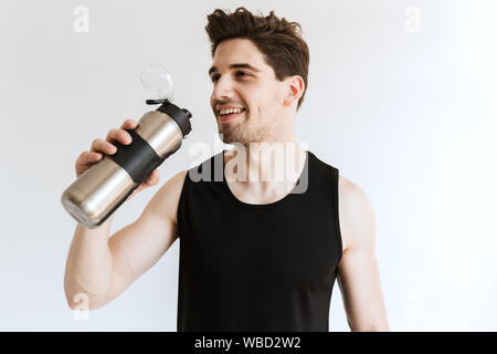 Immagine di un bel lieto di allegro giovane forte uomo sportivo che pongono isolate su muro bianco sullo sfondo di acqua potabile. Foto Stock