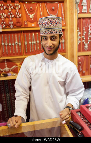 Ritratto di giovane uomo in abiti tradizionali che indossa il cappuccio ricamato di vendita gioielli, Nizwa, Sultanato di Oman Foto Stock