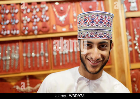 Ritratto di giovane uomo in abiti tradizionali che indossa il cappuccio ricamato di vendita gioielli, Nizwa, Sultanato di Oman Foto Stock